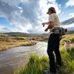 An angler fishing in a scenic Wyoming stream, surrounded by open landscapes, making it one of the best places to go fishing near the Bighorn Mountains.