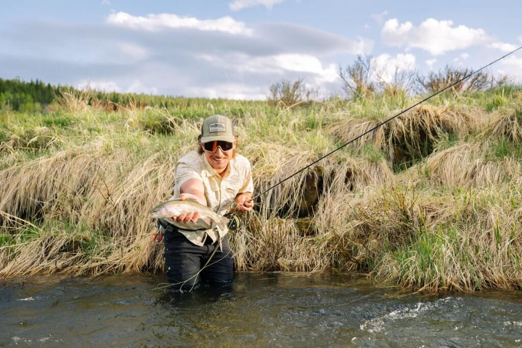 A smiling angler holds a freshly caught trout while fishing near Buffalo, Wyoming, showcasing the area’s excellent trout waters.