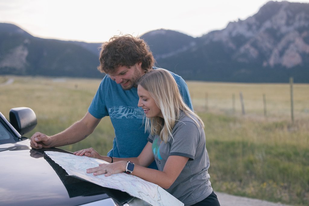 A man and a woman read a map on the side of the road.