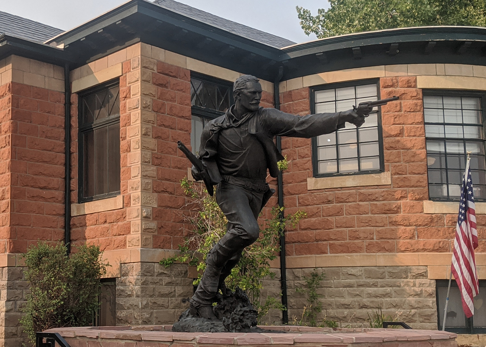 A statute of an outlaw in front of a historic brick building.