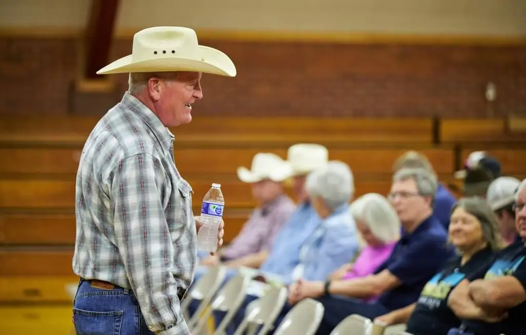 Author Craig Johnson, holding a water bottle on the left side of the image, speaks with audience members before an autograph signing event at Longmire Days.