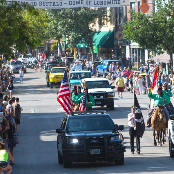 20 Free and Budget-Friendly Things to Do in Buffalo, Wyoming A police car, riders on horseback bolding flags, and a series of vehicles cruise north on Main Street during the annual Longmire Days parade under a banner stretched over the street says, “Welcome to Buffalo – Home of Longmire.”