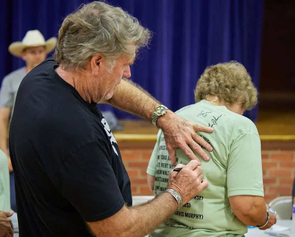 Actor Robert Taylor, who played Sheriff Walt Longmire on the popular Longmire television series, uses a sharpie to sign the back of a green t-shirt being worn by a fan during a Longmire Days autograph session in the gym of the Bomber Mountain Civic Center in Buffalo, Wyoming.