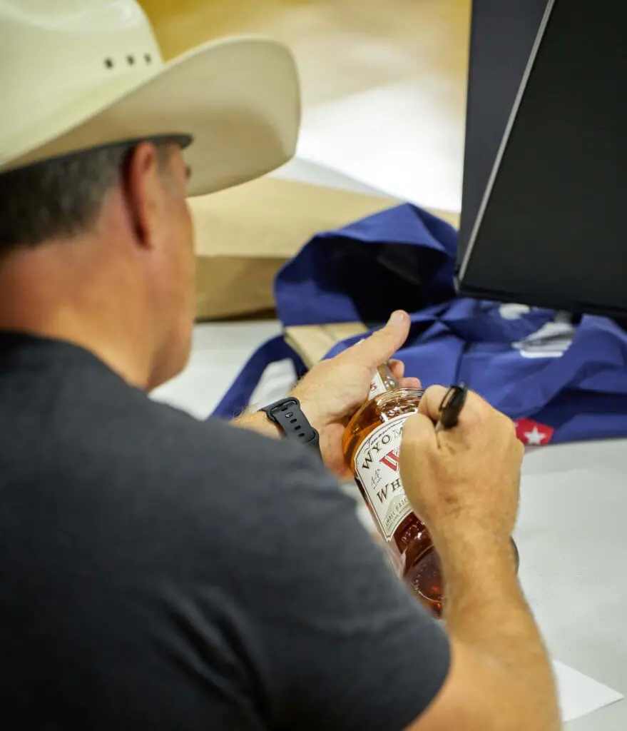 Actor Derek Phillips from the Longmire television series uses a sharpie to sign a whiskey bottle during a Longmire Days autograph session in the gym of the Bomber Mountain Civic Center in Buffalo Wyoming.