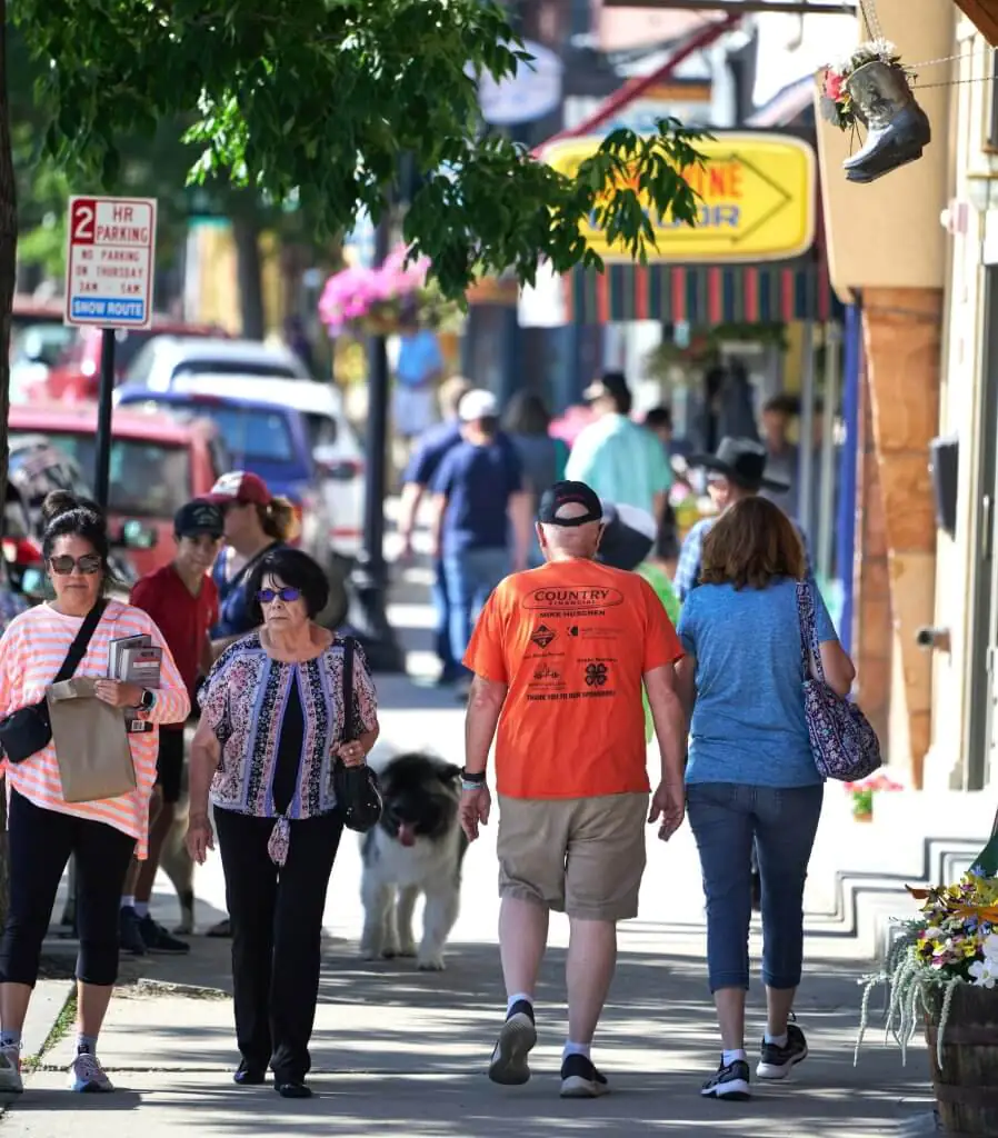 Several people walk toward or away from the camera on Main Street in downtown Buffalo Wyoming during Longmire Days.