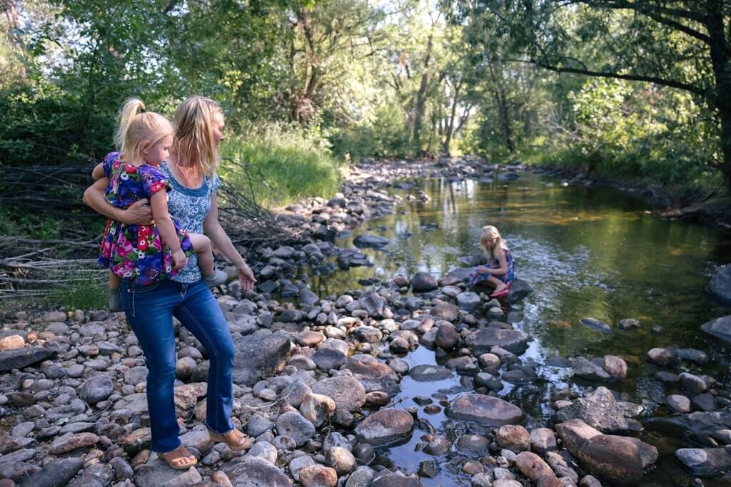 A mother and children exploring the rocky shores of Clear Creek Trail System, a family-friendly outdoor adventure near Buffalo, WY.