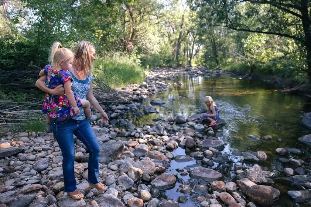 A mother and children exploring the rocky shores of Clear Creek Trail System, a family-friendly outdoor adventure near Buffalo, WY.