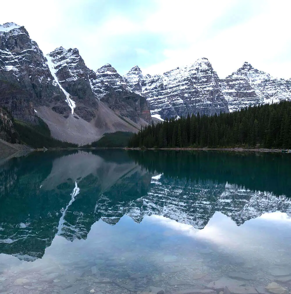 The stunning reflection of snow-capped mountains in a clear lake at Cloud Peak Wilderness, offering unique outdoor experiences for families.