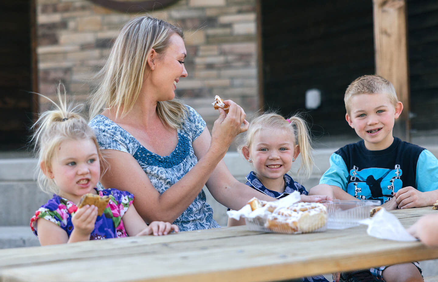 A mother and her three children enjoying a picnic outdoors, highlighting a family-friendly activity in Buffalo, WY.