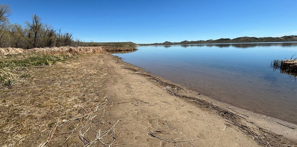 A serene view of Healy Reservoir, showcasing calm waters and a sandy shoreline, perfect for family-friendly activity near Buffalo, WY.