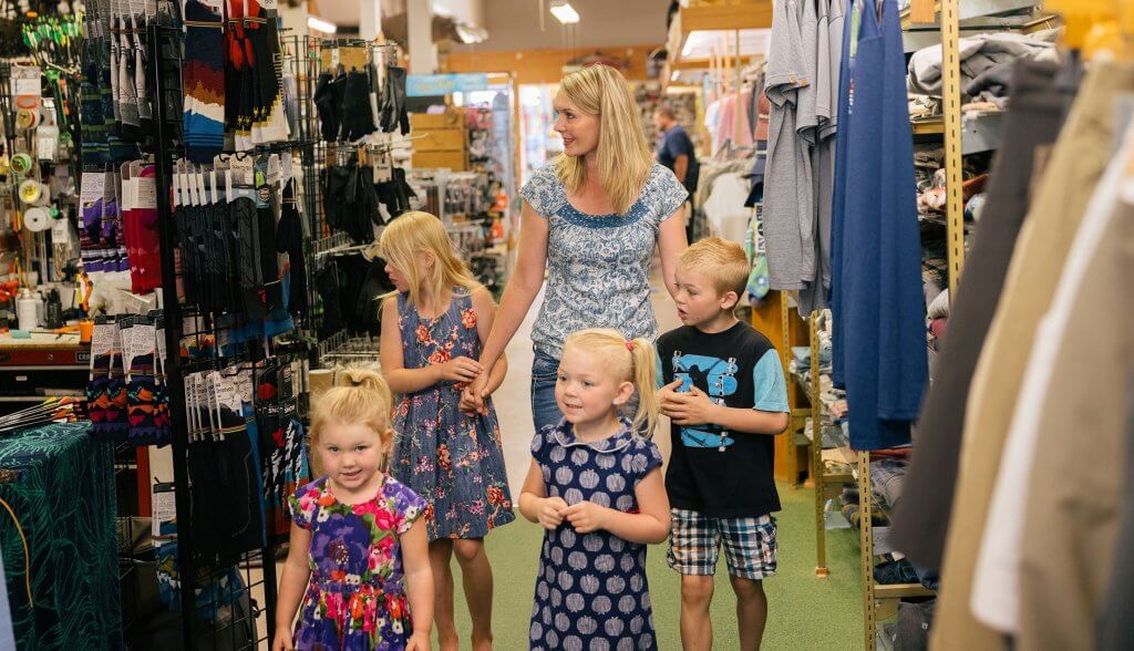 A mother and children exploring Sports Lure store, filled with outdoor gear and clothing, a family-friendly shopping experience in Buffalo, WY.