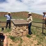 Tour guide explaining the history of Hole in the Wall, a popular tourist site in Buffalo, WY, with visitors listening attentively.