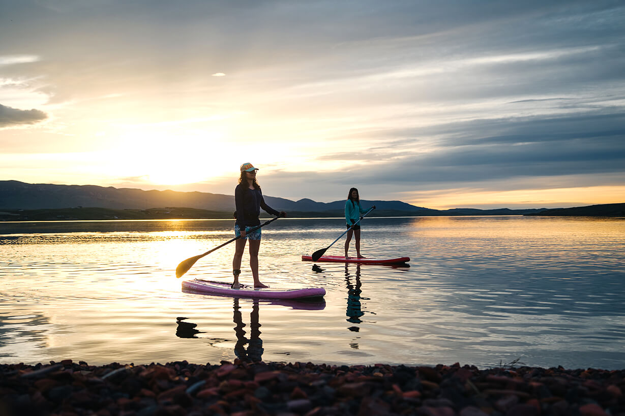 Two paddleboarders enjoying the sunset on Lake DeSmet, a popular spot for outdoor family-friendly activities near Buffalo, WY, with calm waters and scenic mountain views.