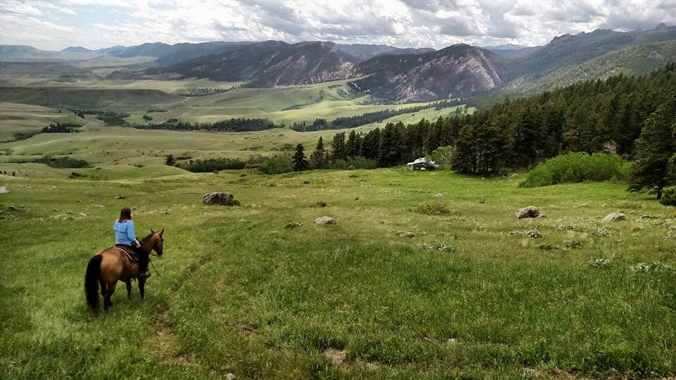 A rider on horseback traveling along South Rock Creek Trail with expansive valleys and distant mountain views, a popular hiking trail near Buffalo, WY.