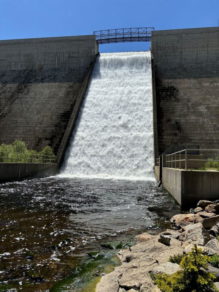 Tie Hack Dam with water flowing over the spillway, located near hiking trails around Buffalo, WY, offering scenic views and outdoor nature exploration.