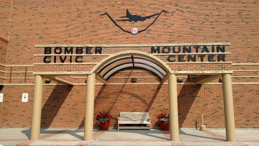 Exterior view of the Bomber Mountain Civic Center in Buffalo, Wyoming, showcasing a welcoming entrance with benches and decorative flower pots, ideal for meeting venues.