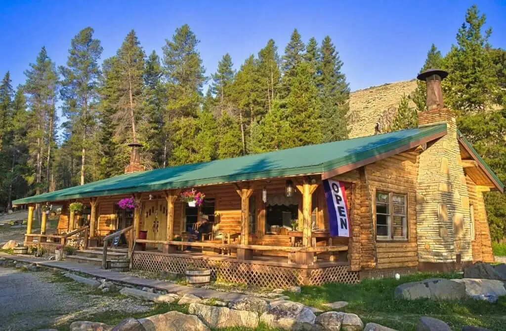 Charming South Fork Mountain Lodge in Buffalo, Wyoming, nestled in a forested setting, featuring rustic log cabin architecture and a welcoming porch.