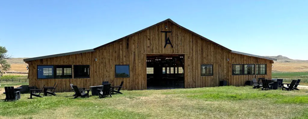 Exterior of the TA Ranch Roadhouse in Buffalo, Wyoming, featuring a rustic wooden structure with open seating and scenic countryside views, ideal for events and gatherings.