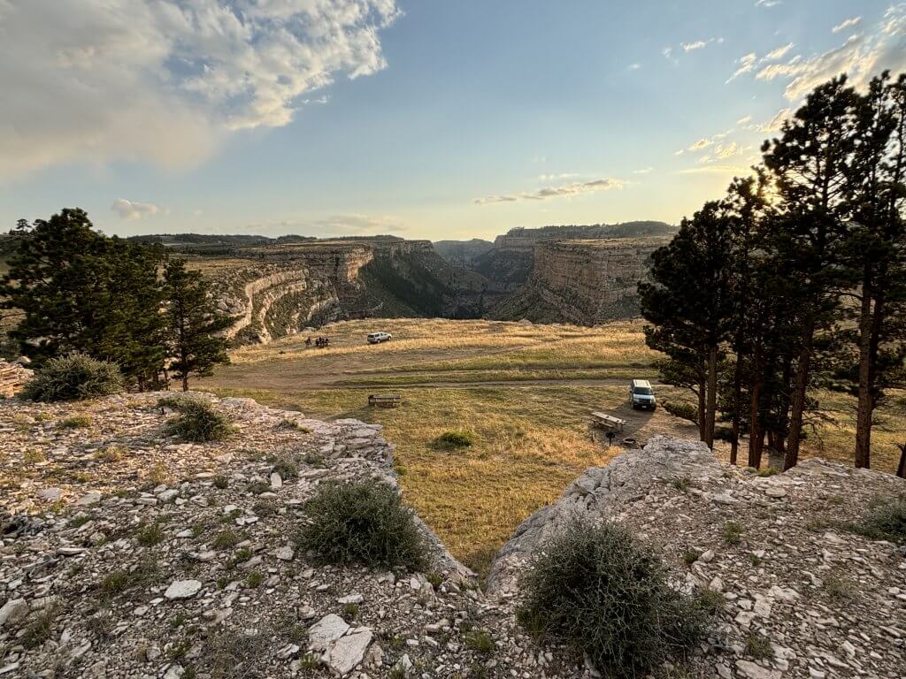 Hole in the Wall Outlaw Cave Campground offering stunning desert camping experience with recreational vehicles positioned among rock formations and prairie landscape at sunset