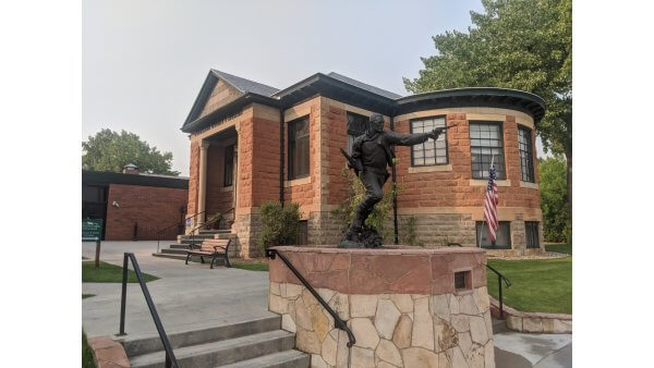 20 Free and Budget-Friendly Things to Do in Buffalo, Wyoming Historic sandstone building housing the Jim Gatchell Memorial Museum in Buffalo, with statue and flag.
