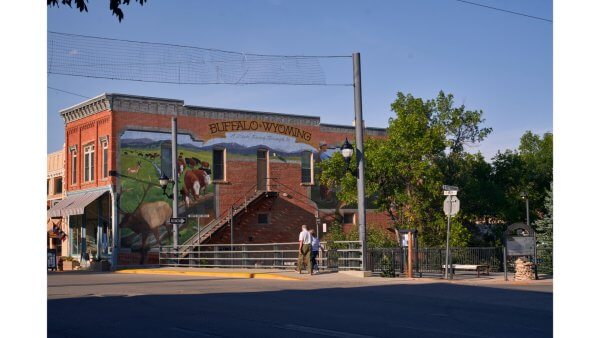 20 Free and Budget-Friendly Things to Do in Buffalo, Wyoming Mural in downtown Buffalo, Wyoming, painted on a red-brick building, depicting a cowboy, elk, and cattle with the words “Buffalo, Wyoming