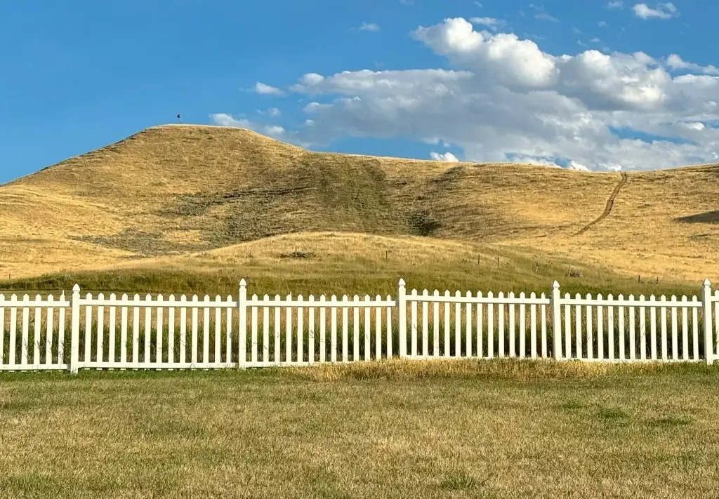 A white fence in front of the Fort Phil Kearny Cemetery Pilot Knob, a haunted place in Johnson County, WY.