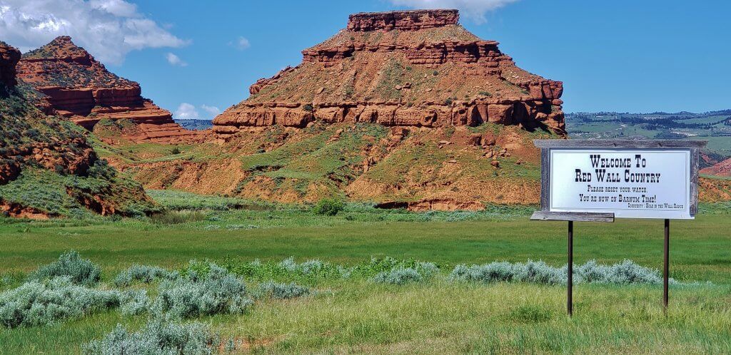 Hole in the Wall Rock and Welcome sign to Red Wall County near Kaycee, Wyoming