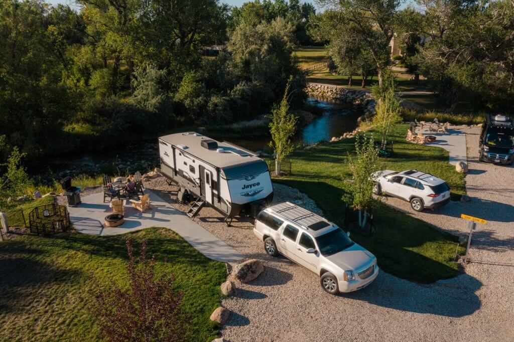 An SUV with a camper hitched to the back at a campsite with a small patio and grass at Buffalo KOA Journey