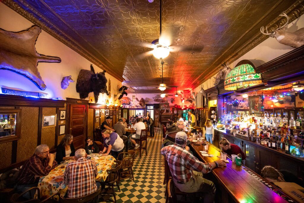 Guests and visitors partaking in drinks and food at the bar at the Occidental Hotel in Buffalo, Wyoming